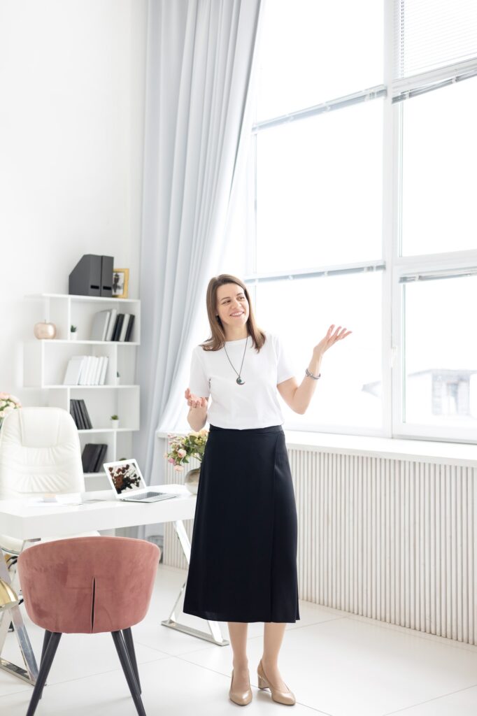a young female coach works in a home office in a light interior with a laptop