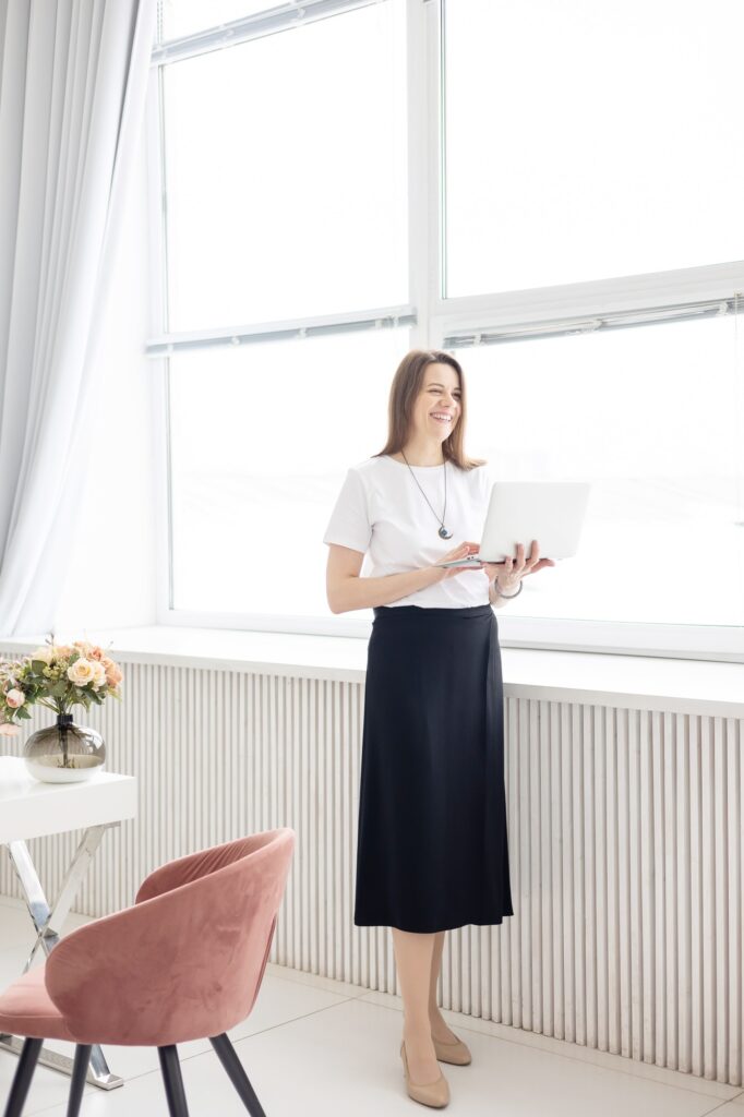 a young female coach works in a home office in a light interior with a laptop