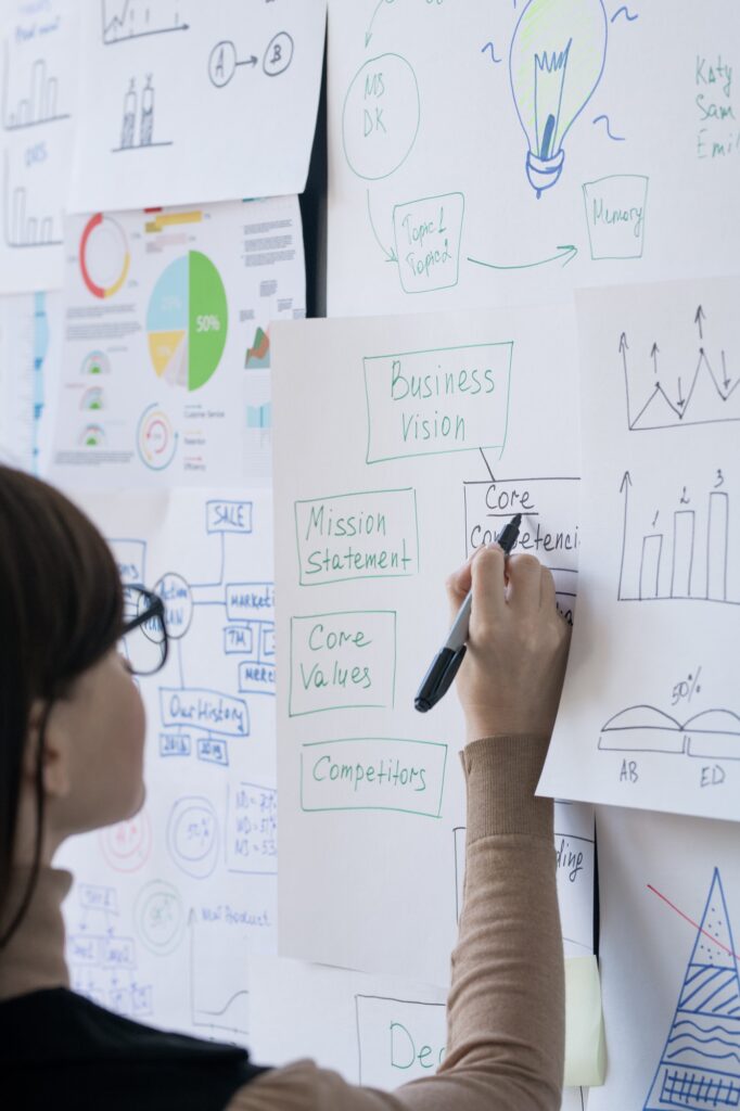 Young female broker or coach pointing at one of papers with flow charts